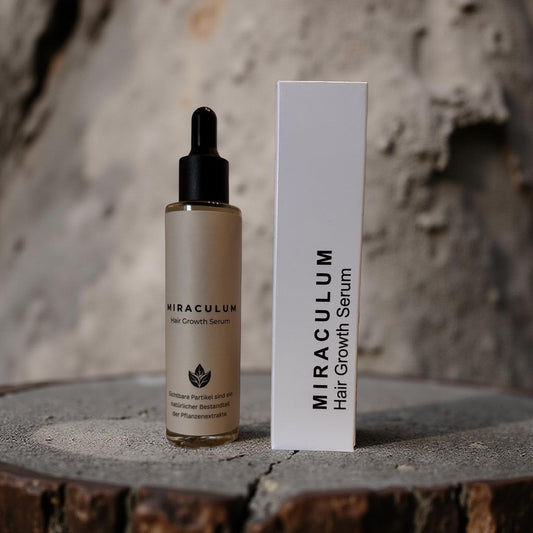Dasifey MIRACULUM Haarserum – Flasche mit Pipette neben Verpackung vor steinigem Hintergrund.