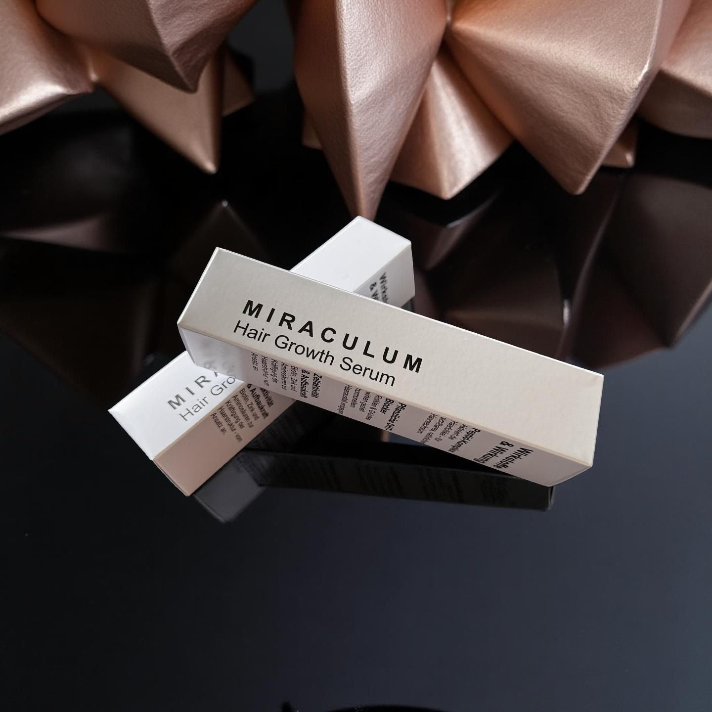 Verpackung von Dasifey MIRACULUM Haarserum – Produktboxen auf glänzend schwarzer Oberfläche.